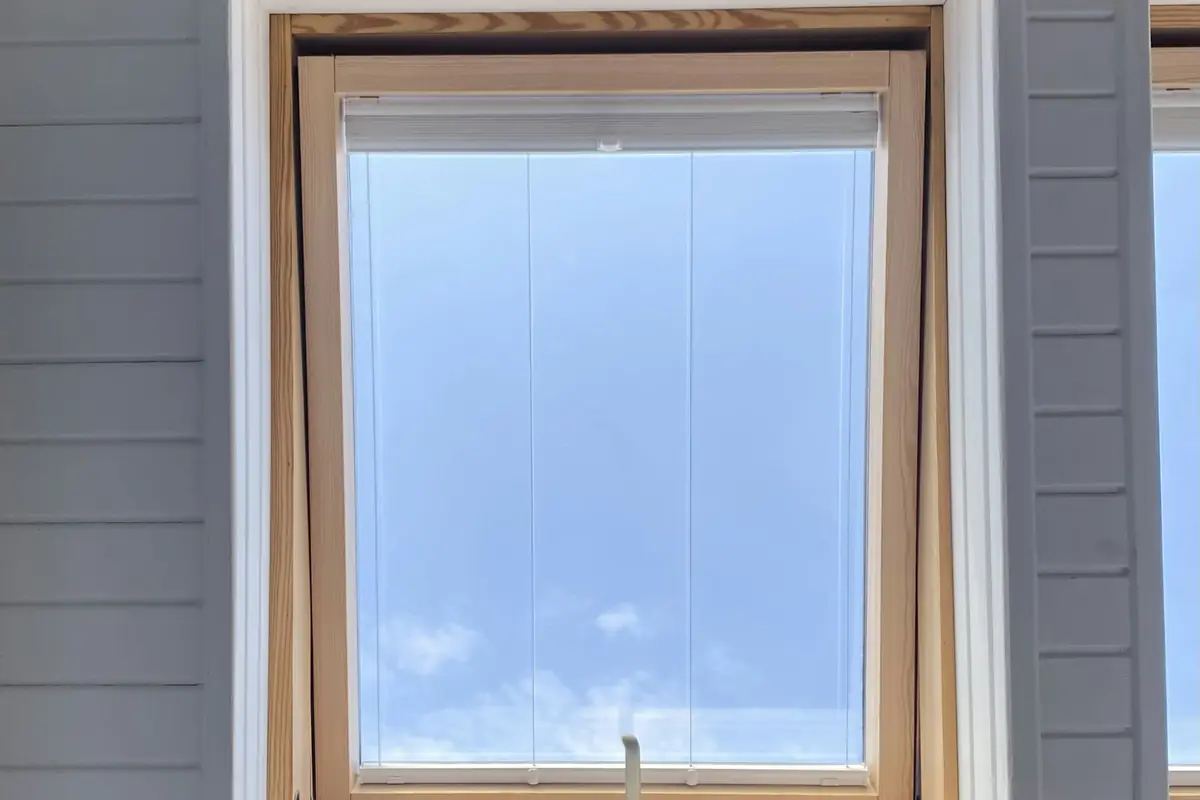 A new wood-framed window set into gray siding with white trim