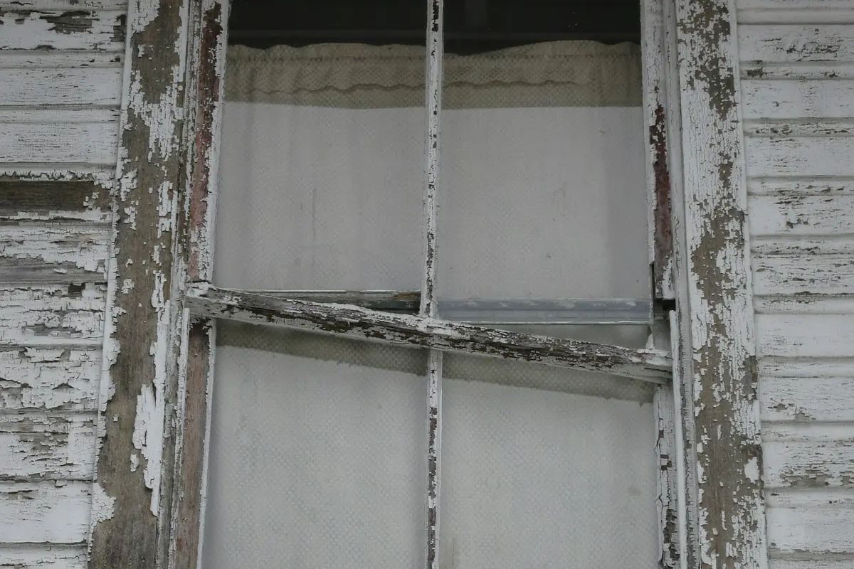 An old wood double-hung window with peeling white paint